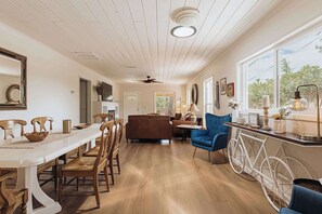 A dining area with a long table and chairs, a blue sofa, and a bicycle wheel.