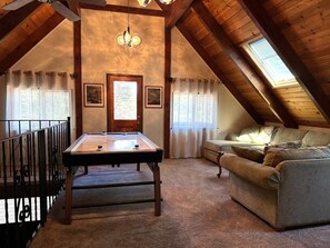 Acogedor cuarto en ático con mesa de billar, sofá y candelabro.