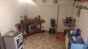 A compact kitchen with a built-in oven, a small television, and various kitchen appliances. - Rustic house with all the charm of the coast. (Maraú)