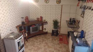 A compact kitchen with a built-in oven, a small television, and various kitchen appliances. - Rustic house with all the charm of the coast. (Maraú)
