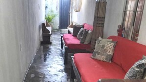 A narrow hallway with a wet floor, a red sofa with patterned cushions, and a wooden bench. - Rustic house with all the charm of the coast. (Maraú)