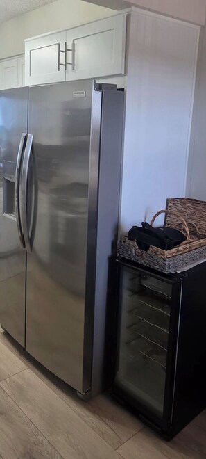 A stainless steel refrigerator with a freezer compartment, a built-in ice maker, and a wine cooler drawer. - Coastal Luxury at Surf Club | Direct Oceanfront | Resort-Style Amenities (Palm Coast)