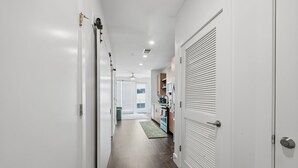 A hallway with a kitchen area, a door with a window, and a ceiling fan. - Modern West Midtown Retreat -Balcony + Pool + Gym (Atlanta)