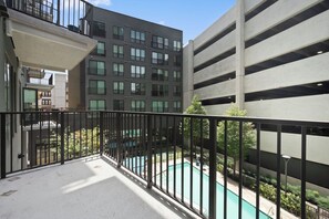 Ein Wohngebäude mit einem Balkon, der einen Swimmingpool überblickt.