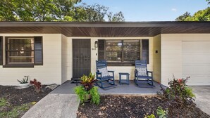 A two-story house with a front porch, two rocking chairs, and a garage. - Historic Downtown Ocala Haven~Peaceful~Near WEC~Fenced~Dogs Ok~Sleeps 8 (Ocala)