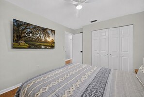 A bedroom with a bed, a wardrobe, a ceiling fan, and a wall-mounted picture.