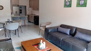Un salon moderne avec un canapé en cuir, une table basse en bois et un coin repas avec des chaises.