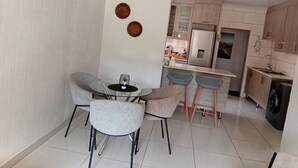 Une cuisine moderne avec un coin repas, comprenant une table ronde avec des chaises, un lave-linge et un réfrigérateur.