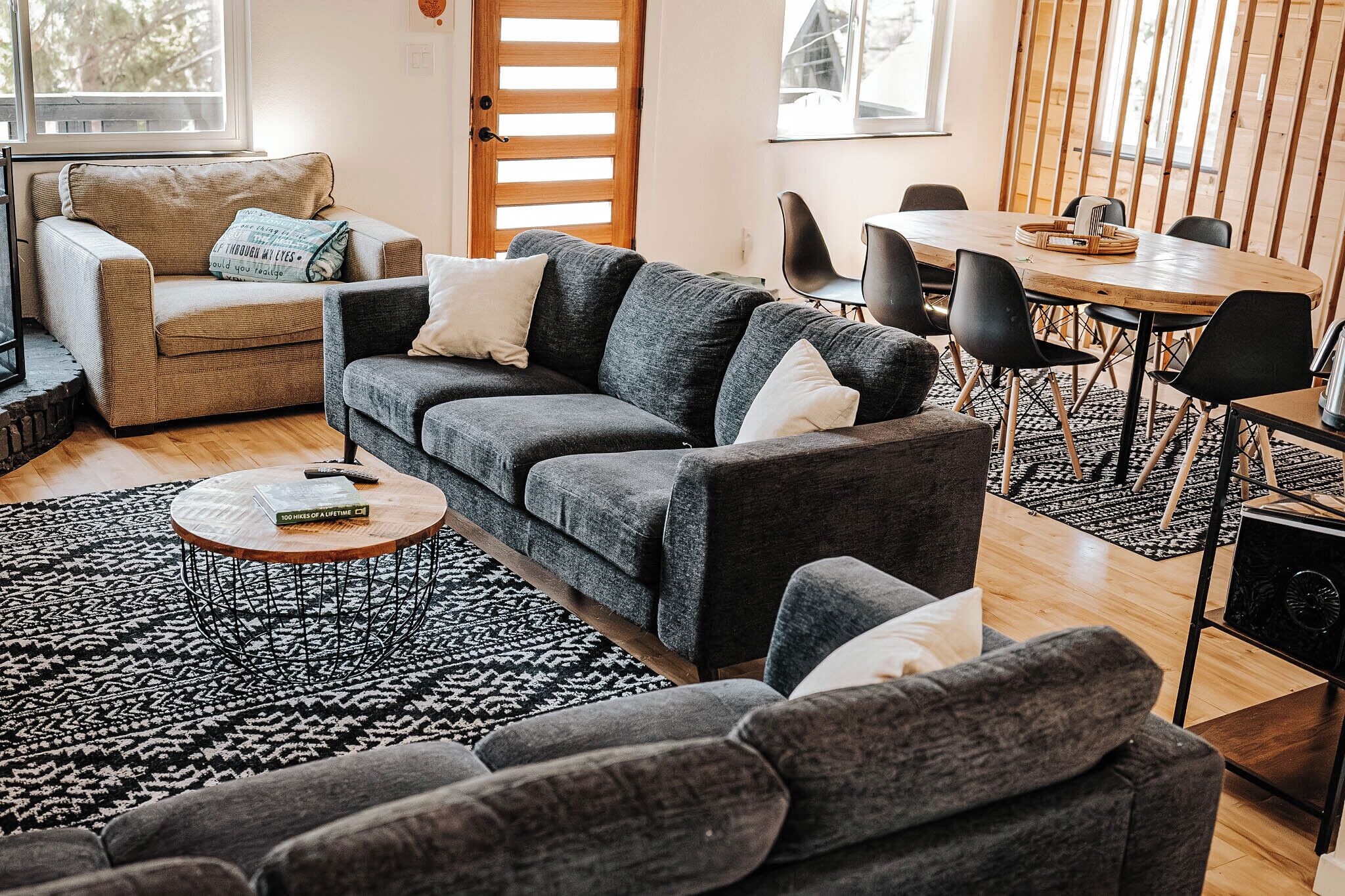 Una sala de estar acogedora con un sofá gris, una mesa de centro y un comedor con una mesa y sillas de madera.