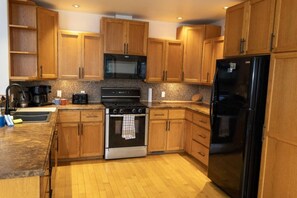 Une cuisine avec des meubles de rangement en bois, une cuisinière, un four à micro-ondes et un réfrigérateur.