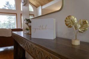 A guest book on a wooden counter with a decorative leaf sculpture beside it.