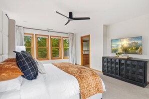 A bedroom with a bed, a TV, a ceiling fan, and a view of the outdoors through large windows. - Hot Tub*A/C*Pool Table*Xbox*Fireplace (Flagstaff)
