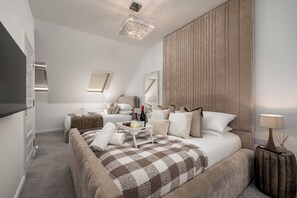 Een moderne slaapkamer met een groot bed, een nachtkastje, een lamp en een spiegel.