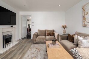 Un salon moderne avec une cheminée, un ensemble de canapés, une table basse et un téléviseur à écran plat.