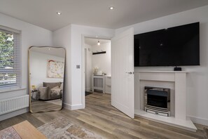 A modern living room with a fireplace, a television mounted above it, and a large mirror on the wall. - Chic 4BR Home | Garden | Free Parking | Maidstone (Kent)