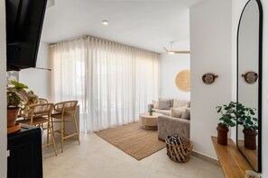 Ein modernes Wohnzimmer mit einer Couch, einem Couchtisch, einem Fernseher und einem Essbereich mit Stühlen und Tisch.