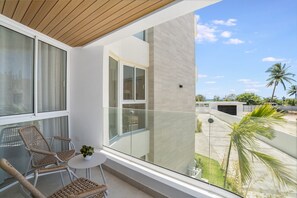 A balcony with wicker chairs, a small table, and a potted plant. - Beach Escape • Ocean View 1BR at Mareal (Cabarete)
