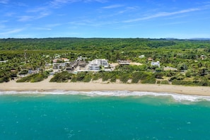 A coastal area with a beach, a residential complex, and a forested hill in the background. - Beach Escape • Ocean View 1BR at Mareal (Cabarete)