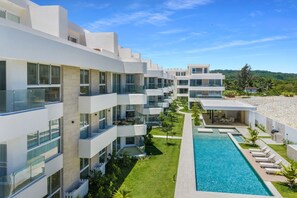 Ein modernes Hotel mit mehreren Balkonen, einem Swimmingpool und Blick auf die umliegende Landschaft.