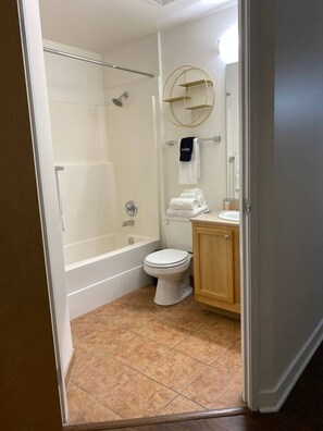 Een badkamer met een douchecabine van glas, een toilet en een wastafel met een houten kastje.