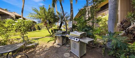 An outdoor grill area with a sign, a metal table, and chairs.