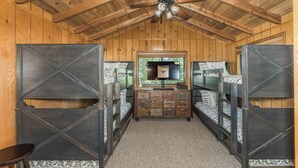 Ein Zimmer mit Etagenbetten, Holzbalkendecke und einer zentralen Kommode mit Schubladen.