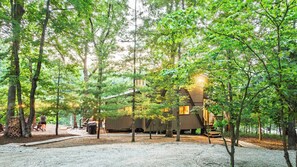 A cabin with a wooden exterior, surrounded by trees and a gravel path. - Longhorn Lakeside Chalet (Beach, Hot Tub, Kayaks) (Innsbrook)