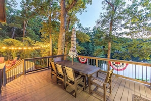A wooden deck with a table and chairs, surrounded by trees and a railing. - Longhorn Lakeside Chalet (Beach, Hot Tub, Kayaks) (Innsbrook)