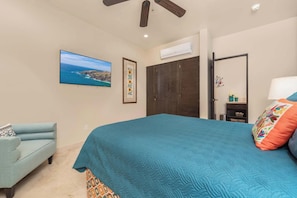 A bedroom with a bed, a chair, a wardrobe, a television, and a ceiling fan. - CCV Quivira - Amazing 2BR Copala Condo w/ Ocean Views (Cabo San Lucas)