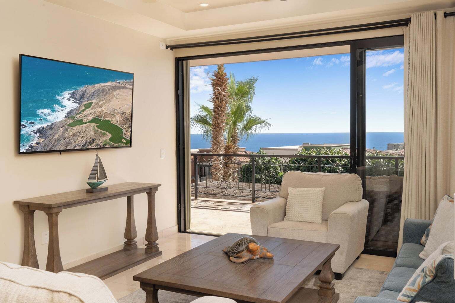 Een balkon met uitzicht op zee, een bank, een tafel en een schilderij.