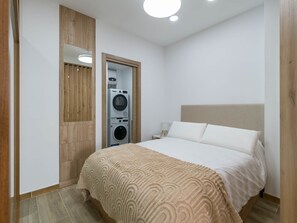 A bedroom with a bed, a washing machine, and a wooden wardrobe. - Paraíso Canteras - Beachfront Living! (Las Palmas de Gran Canaria)