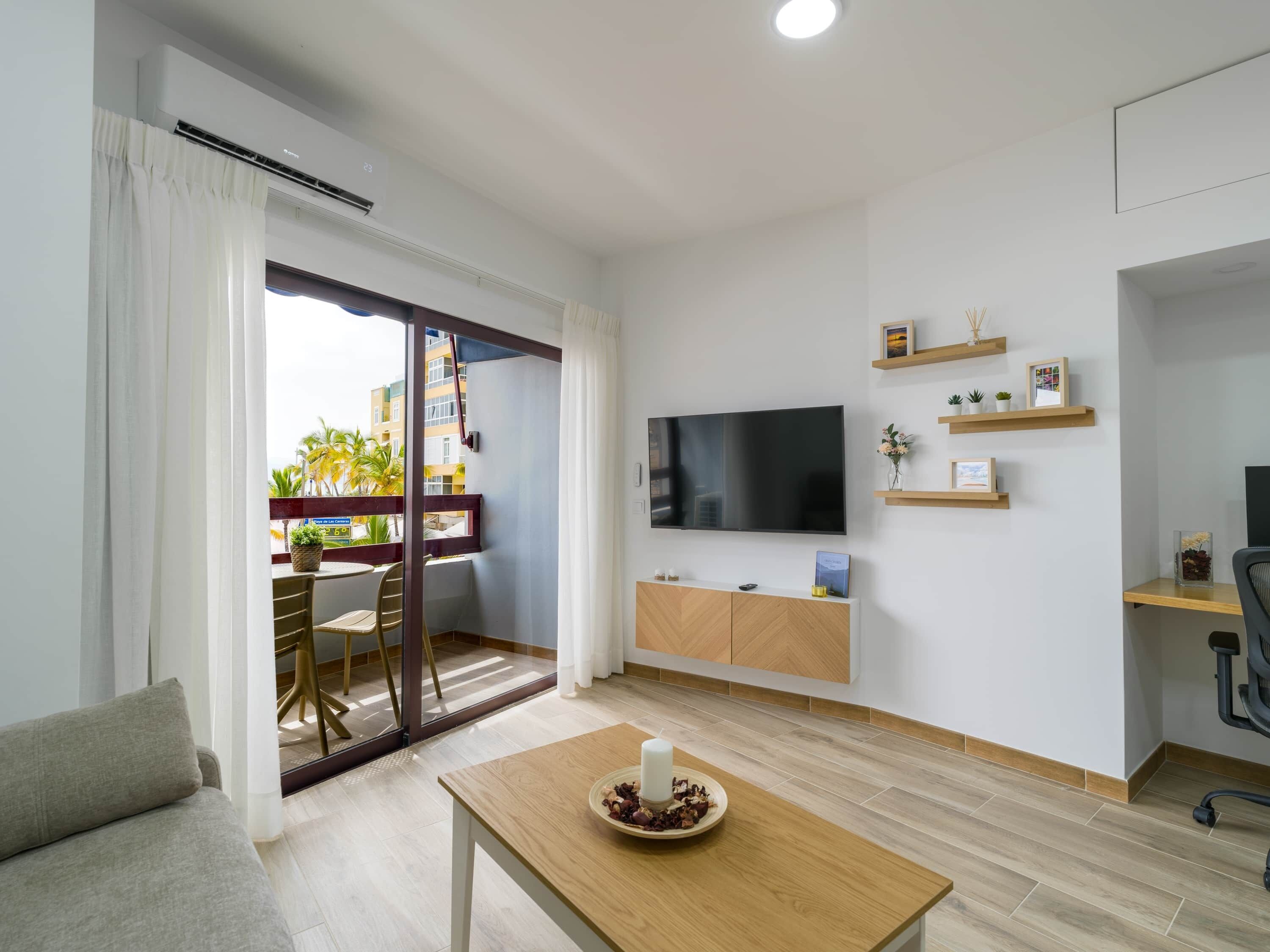 Ein modernes Wohnzimmer mit Flachbildfernseher, Holzmöbeln und einem Balkon mit Blick.