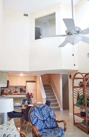 A compact living space with a dining area, kitchen, and a staircase leading to an upper level. - Royal Mansions 3302 (Cape Canaveral)
