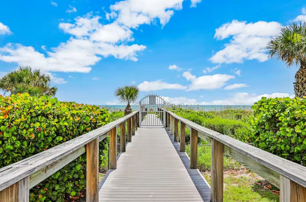 A wooden boardwalk leading to a gazebo with a view of the ocean.