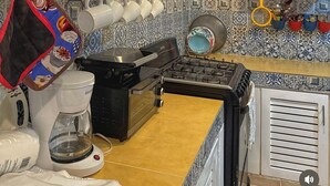 Une cuisine équipée d’une cuisinière, d’une machine à café, ainsi que de différents plats et ustensiles rangés sur des étagères.