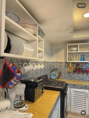 A kitchen with a stove, coffee maker, and various dishes and utensils on shelves. - VillasMana1 PLayaBonitaLasTerrenas 3Bedrom NearBeach (Las Terrenas)
