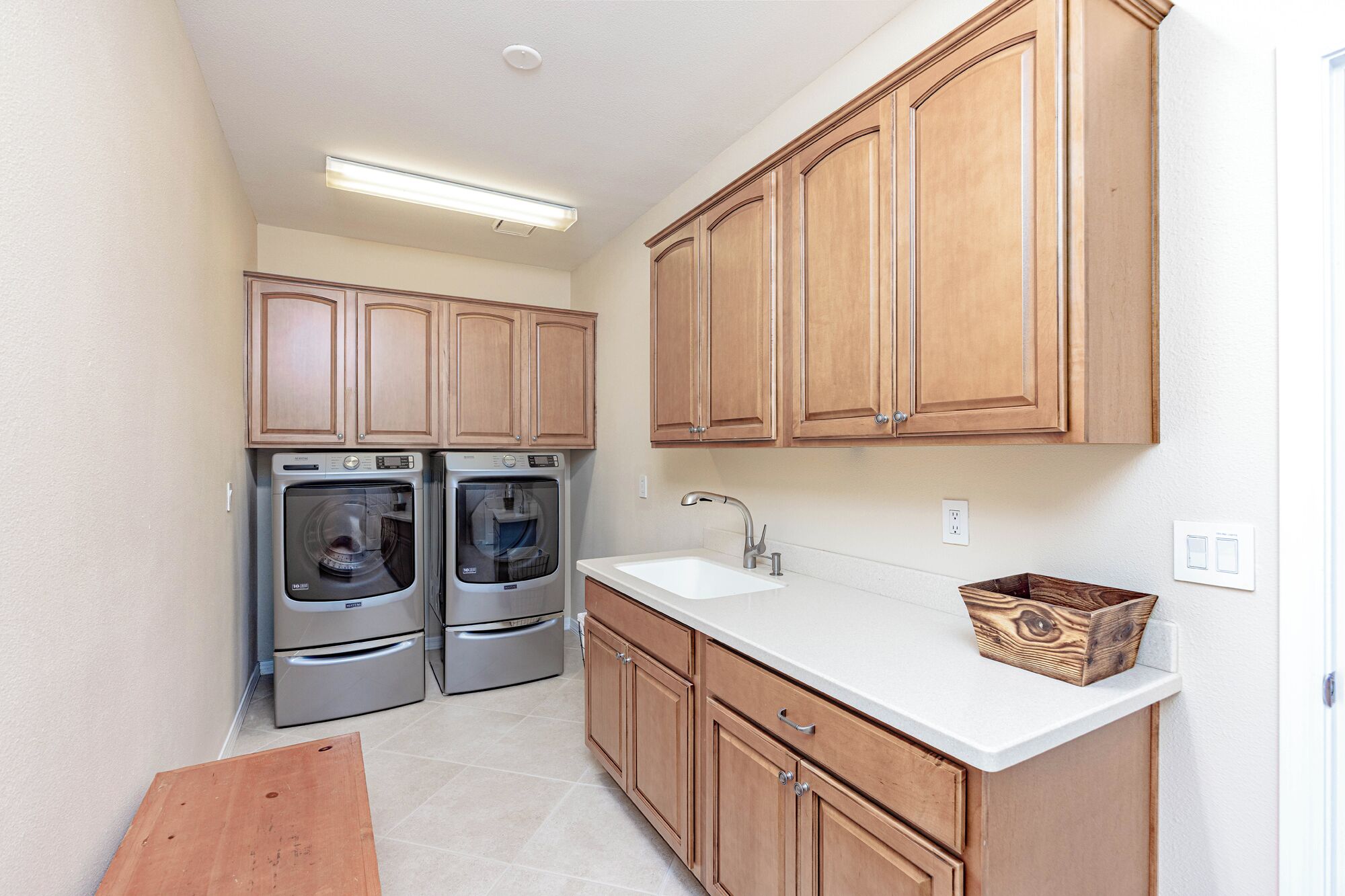 A compact kitchen with wooden cabinets, a double sink, and two stainless steel appliances.