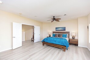 A bedroom with a bed, two bedside tables, a ceiling fan, and a door leading to another room. - Spacious 5-bedroom house in serene Lake Havasu with pool, and Lake view (Lake Havasu City)
