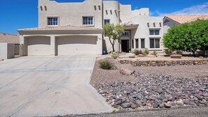 Una propiedad residencial con garaje, entrada para vehículos y jardín frontal ajardinado con rocas y plantas.