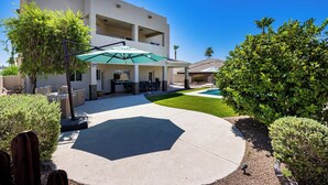 Edificio de dos plantas con patio, mobiliario exterior y piscina.