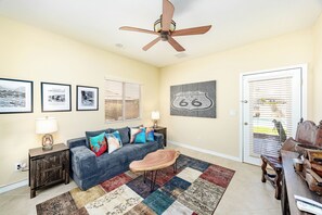 A living room with a sofa, a coffee table, a ceiling fan, a rug, and a door with a window. - Spacious 5-bedroom house in serene Lake Havasu with pool, and Lake view (Lake Havasu City)