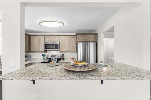 Cocina moderna con encimeras de granito, electrodomésticos de acero inoxidable y armarios de madera.