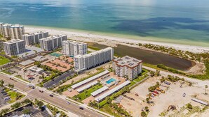 A high-rise hotel with multiple floors, a swimming pool, and a beach view. - Beachfront Escape with Pool & Island Fun Steps from the Sand - Sand Caper 509 - Roelens (Fort Myers Beach)