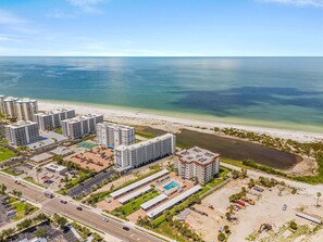 A high-rise hotel with multiple floors, a swimming pool, and a beach view. - Beachfront Escape with Pool & Island Fun Steps from the Sand - Sand Caper 509 - Roelens (Fort Myers Beach)