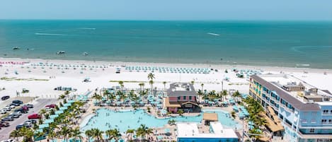 Un resort con una piscina amplia, zona de playa y varios edificios.