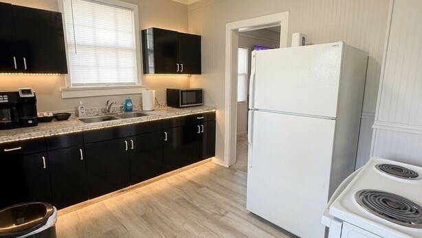Una cocina moderna con armarios negros, un refrigerador blanco, una estufa y un microondas.