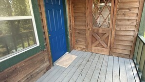 Un porche de madera con una puerta azul y una ventana.