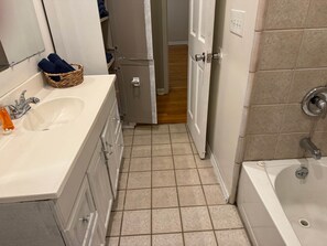 A bathroom with a sink, mirror, and bathtub.