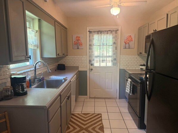 A compact kitchen with a sink, stove, refrigerator, and a window with curtains. - 3/1 good parking close to construction projects (Alexandria)
