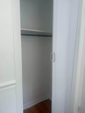 Ein schmaler, weißer Kleiderschrank mit einer einzelnen Ablagefläche.